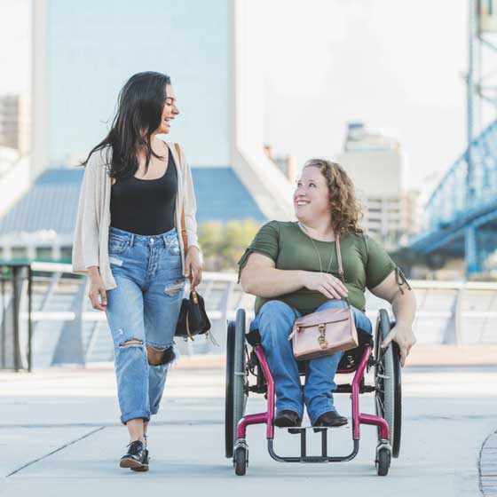 Two friends, one in a wheelchair, crossing a bridge
